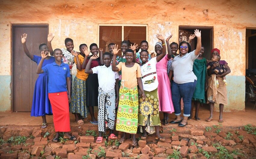 A group of young people standing together and raising their hand for the picture.