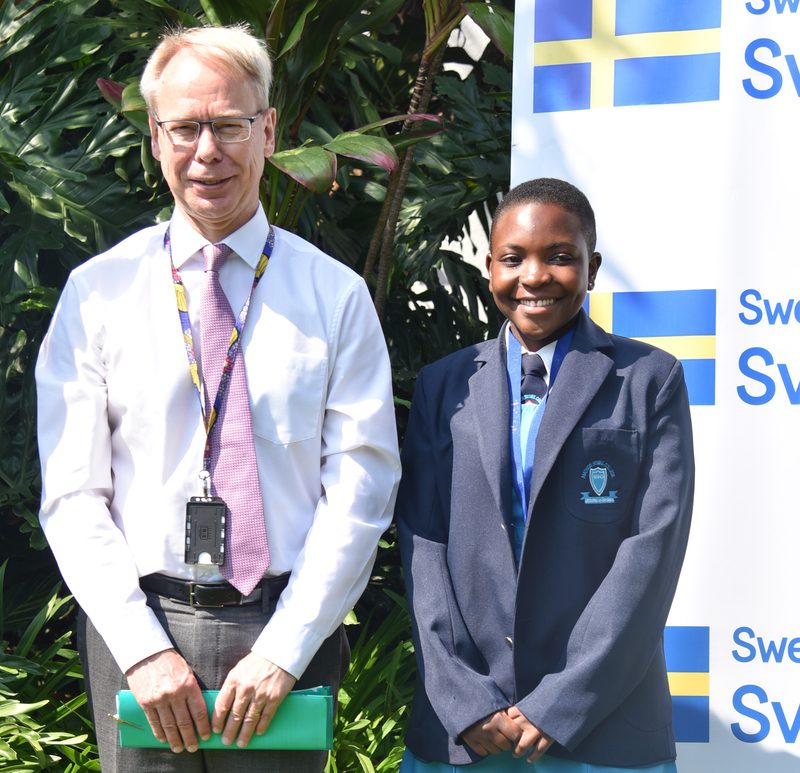 Vimbainashe standing next to Swedish Ambassador to Zimbabwe Per Lindgarde.