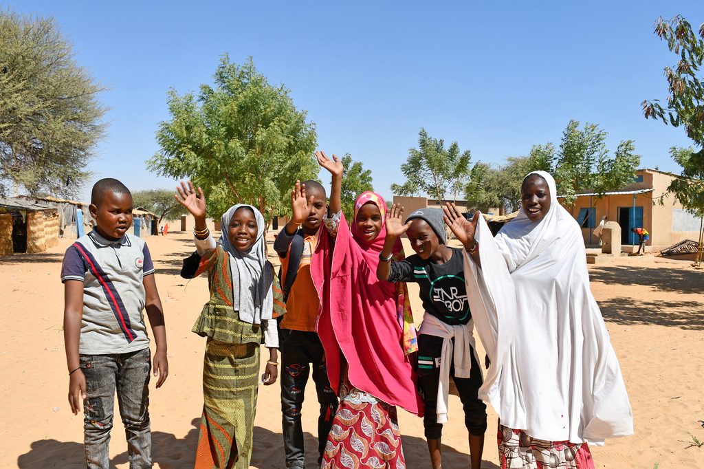 Group of children standing and waving at the camera