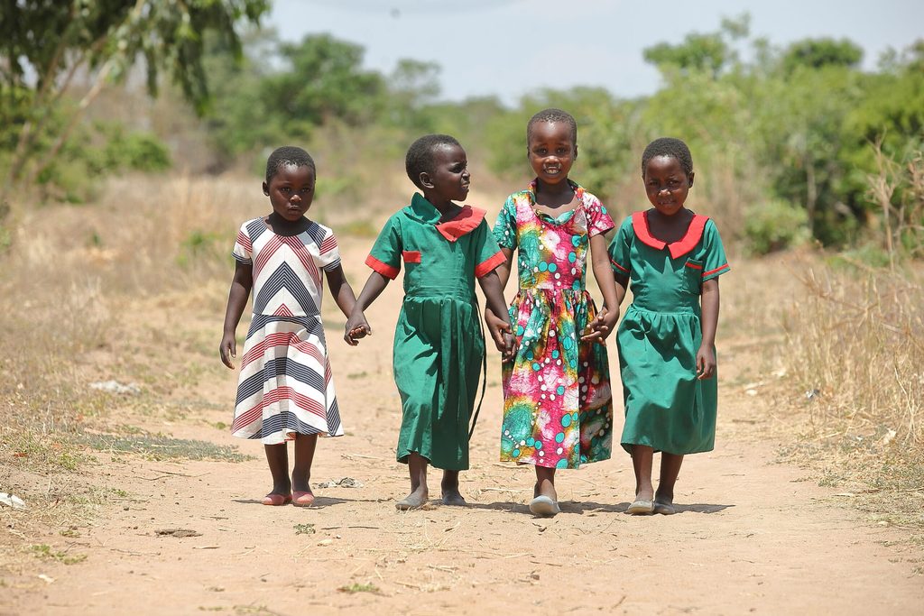 Girls holding hands walking to school