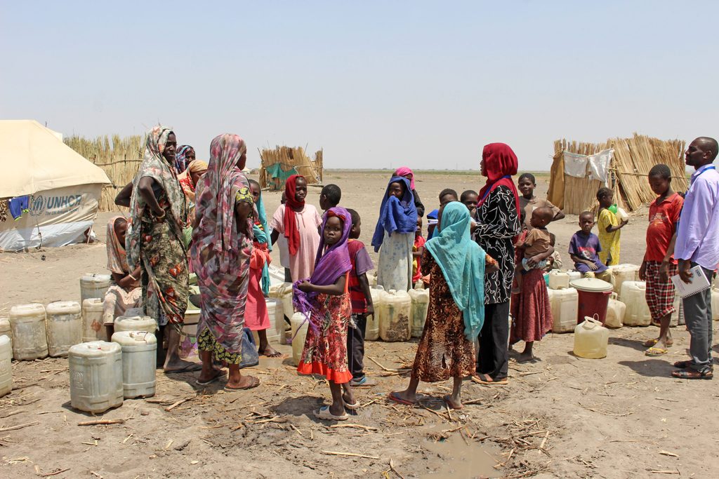 Women and children collect water from water point in displacement camp.