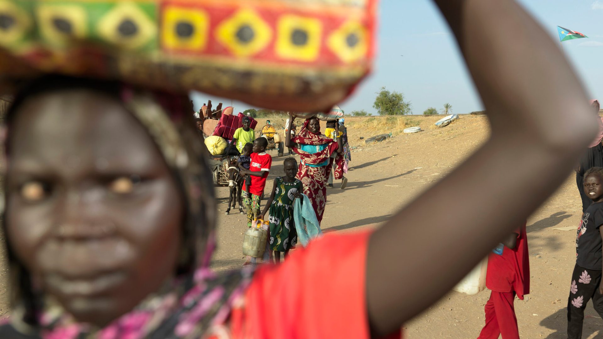 Families walking, carrying belongings fleeing conflict.