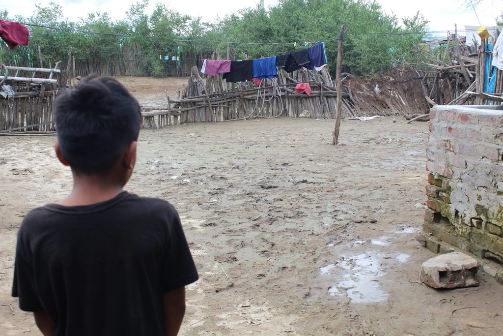 Niño junto a terreno que se vio afectado por inundación