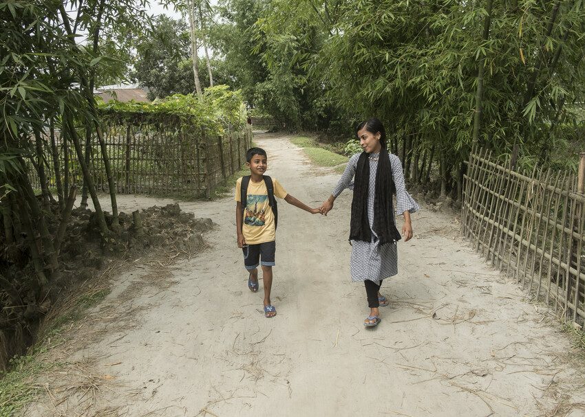Rozina, 19, walks her brother to school in Kurigram district 
