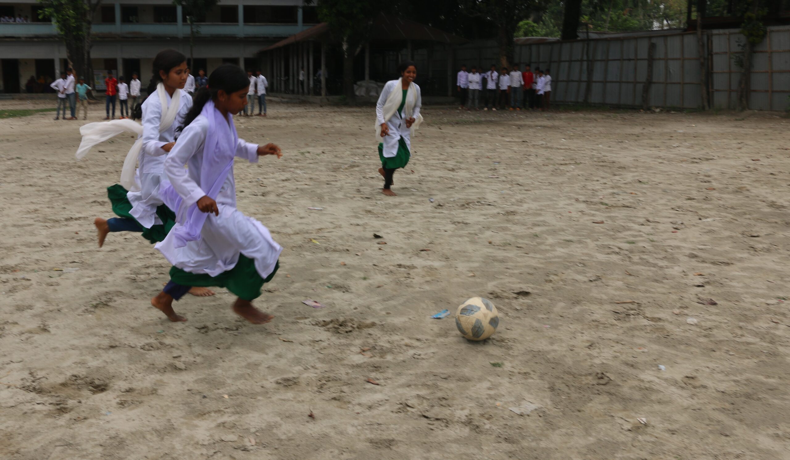 Lila is playing football with others © Plan International