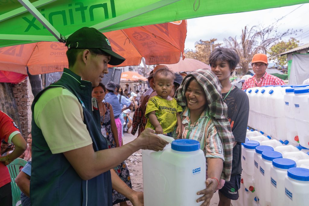 Plan Myanmar staff distribute jerry cans to people staying at a resettlement site in Sagaing region. © Plan International