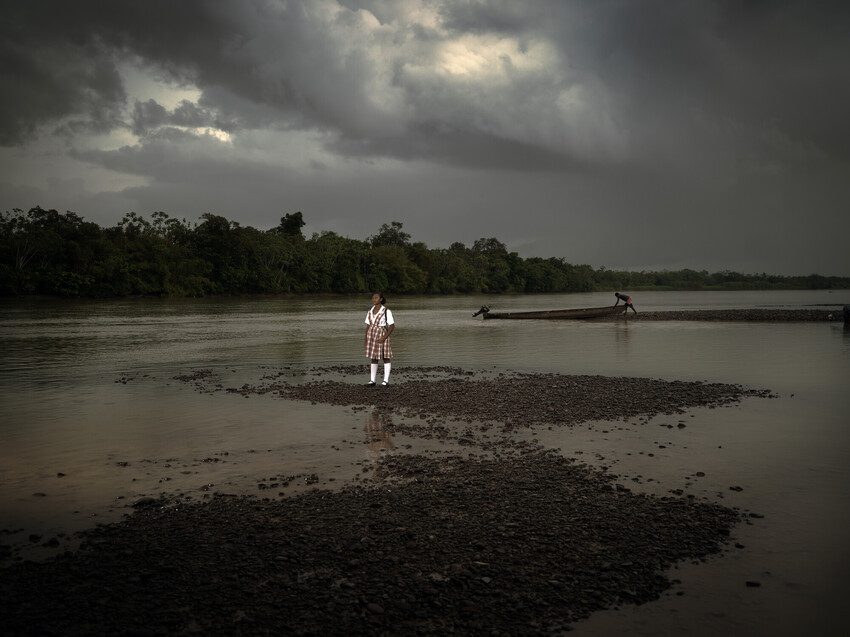 Isabel stands on the edge of the river
