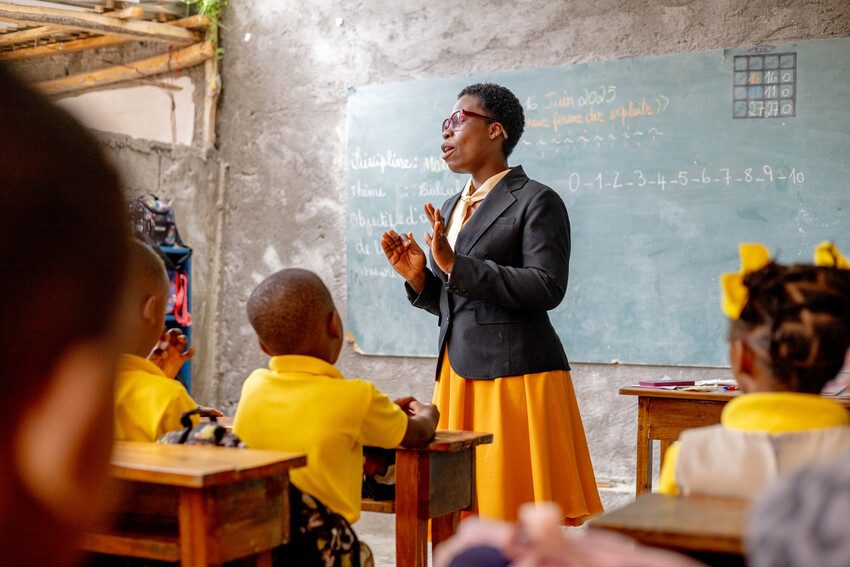 Rose, standing in front of a class of school children.