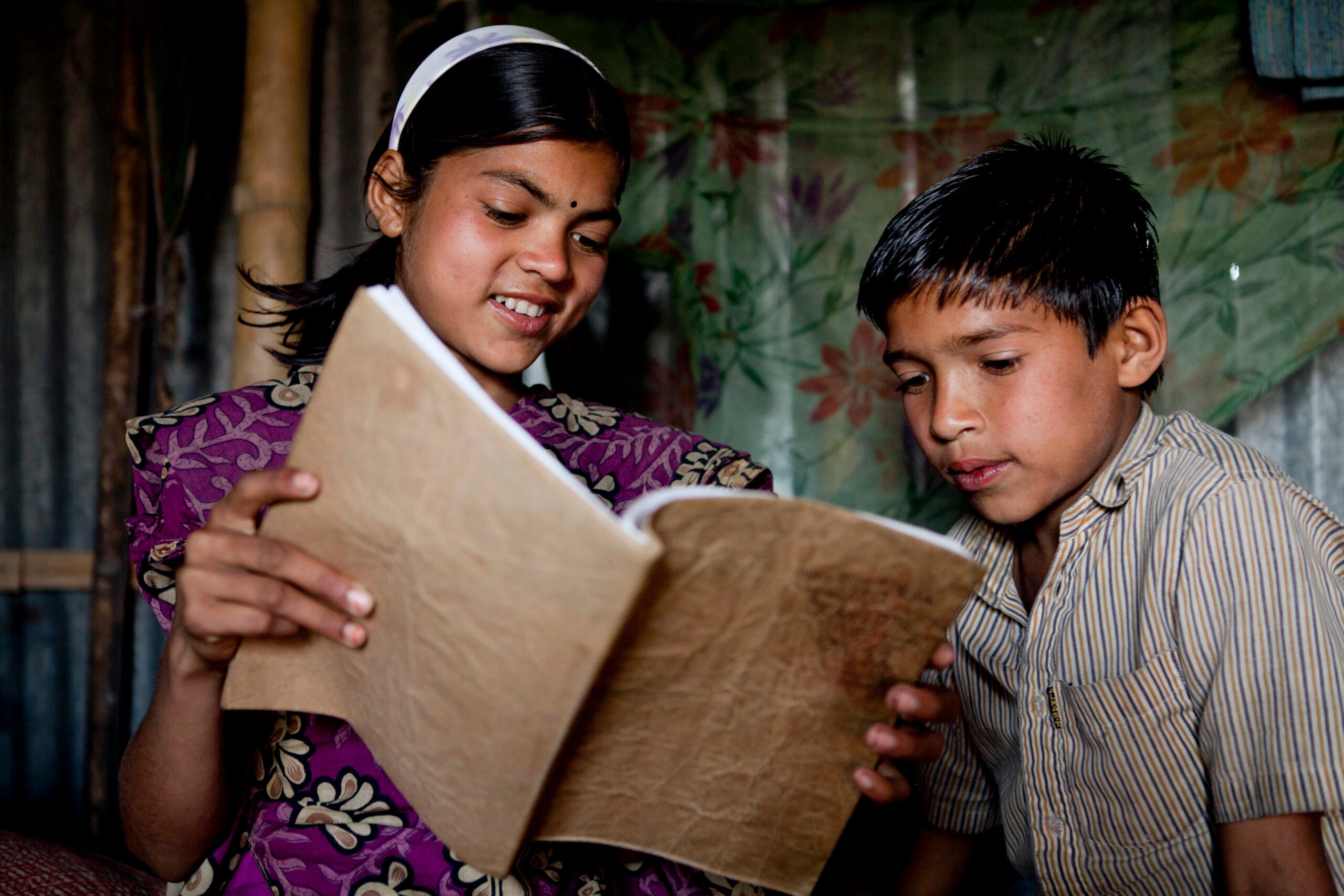 Girl and boy reading a book, receiving inclusive quality education.