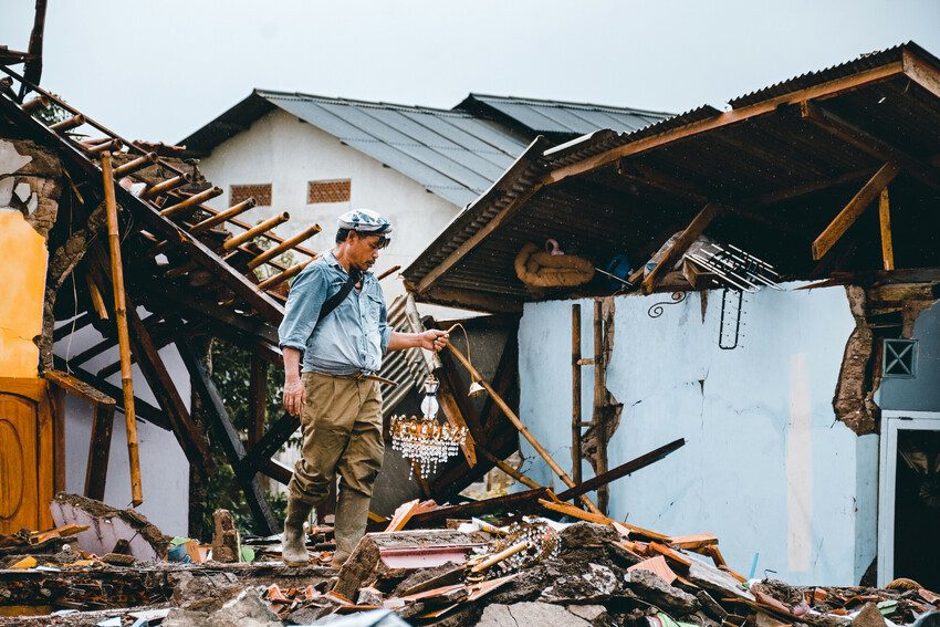 A man salvages some possessions from a collapsed house