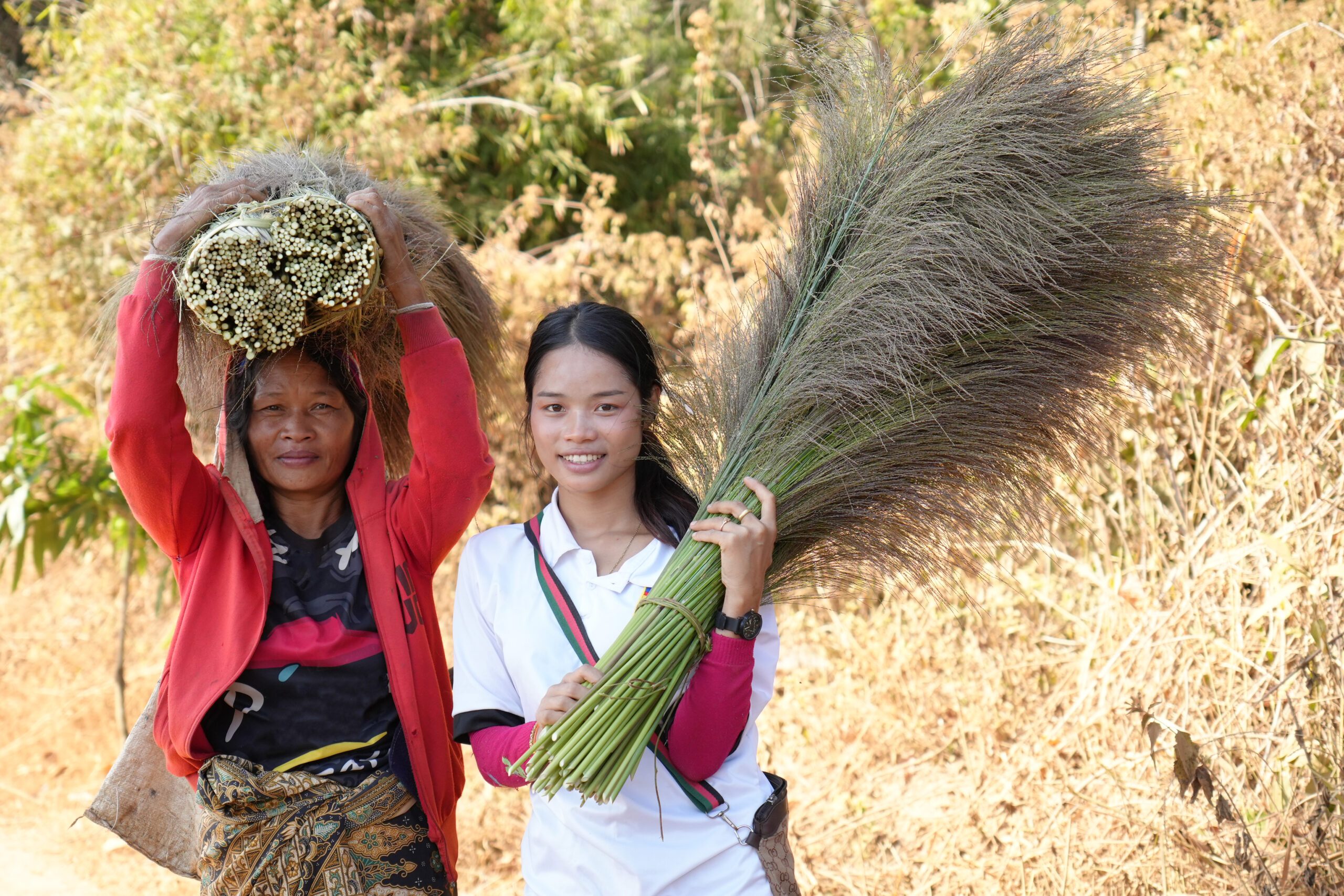 Vone and her daughter holding broom grass flowers.
