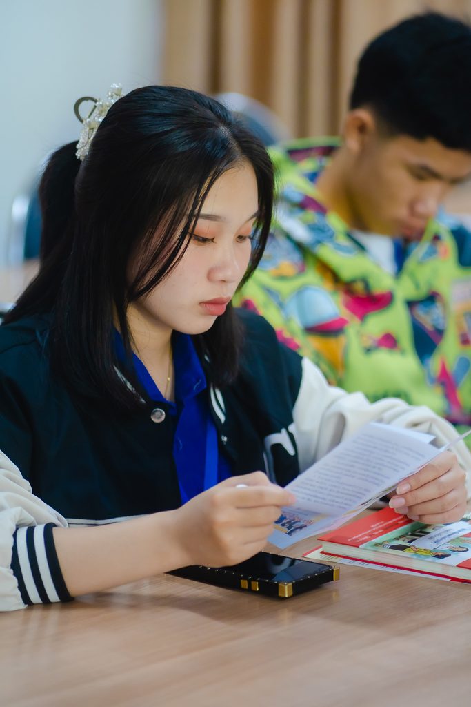 Chanpheng reads a pamphlet about SRHR and practices her script.