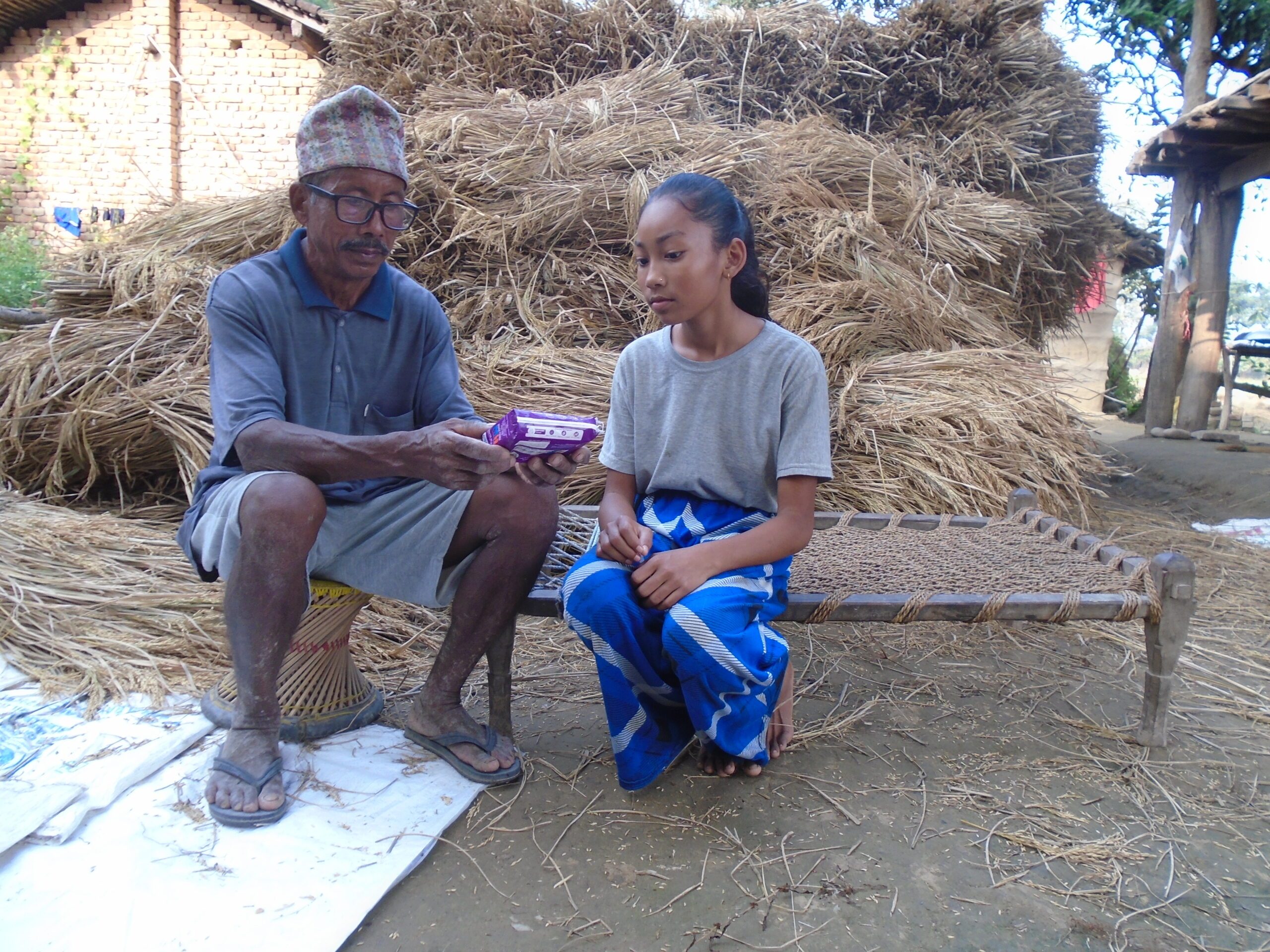 Tilakram talking about sanitary pads with his granddaughter.