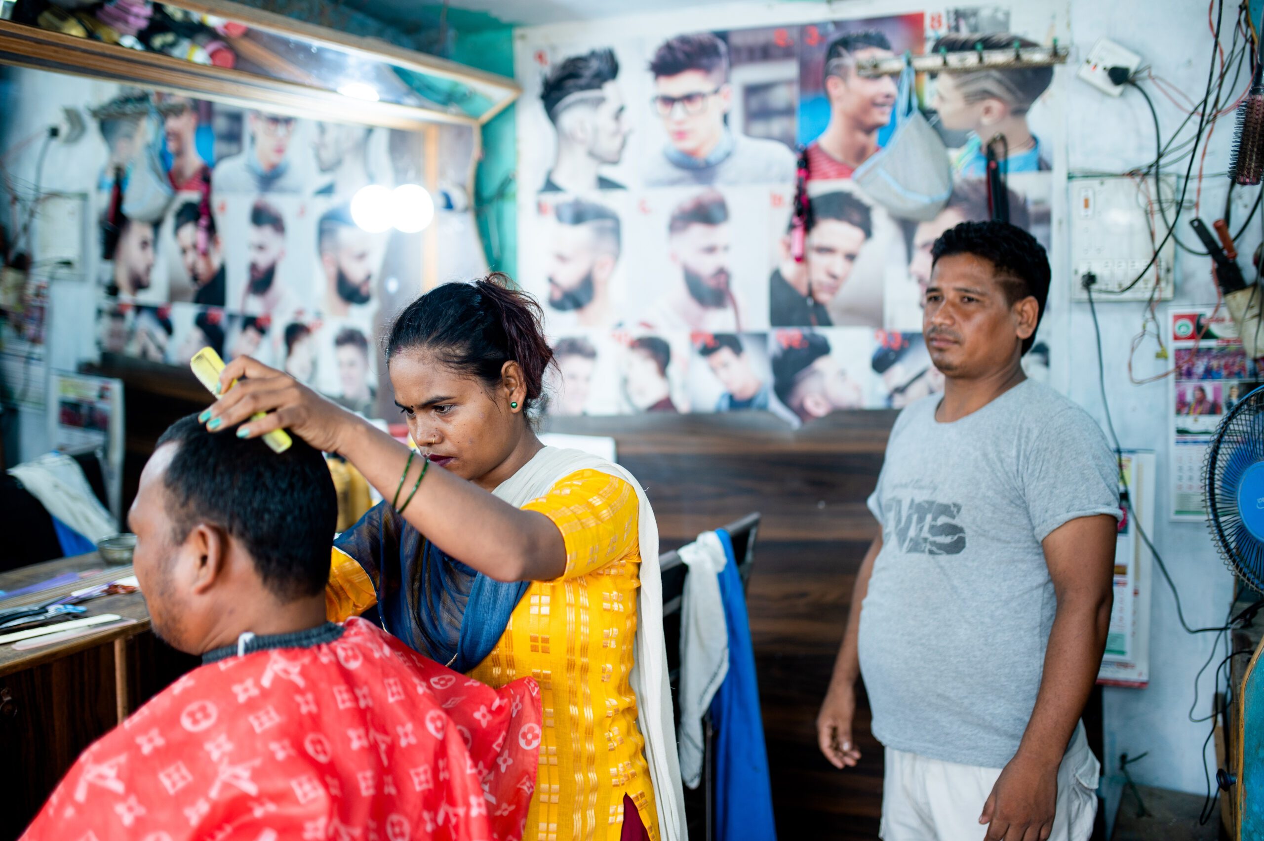 The trainer watches Rampati cut hair. 