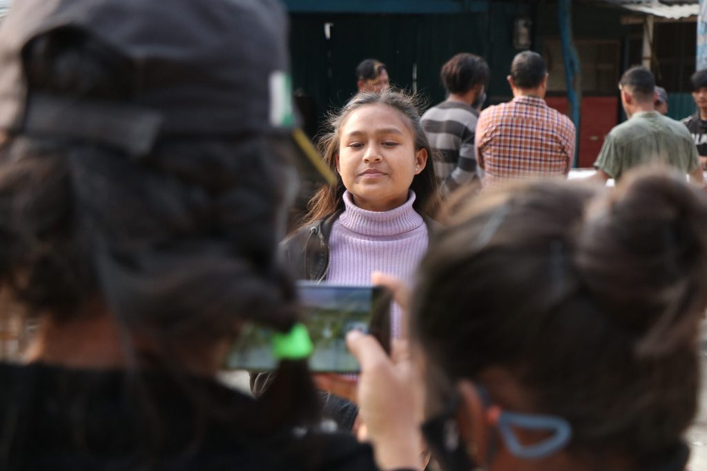 Two youth reporters using their mobile phone to film a story.