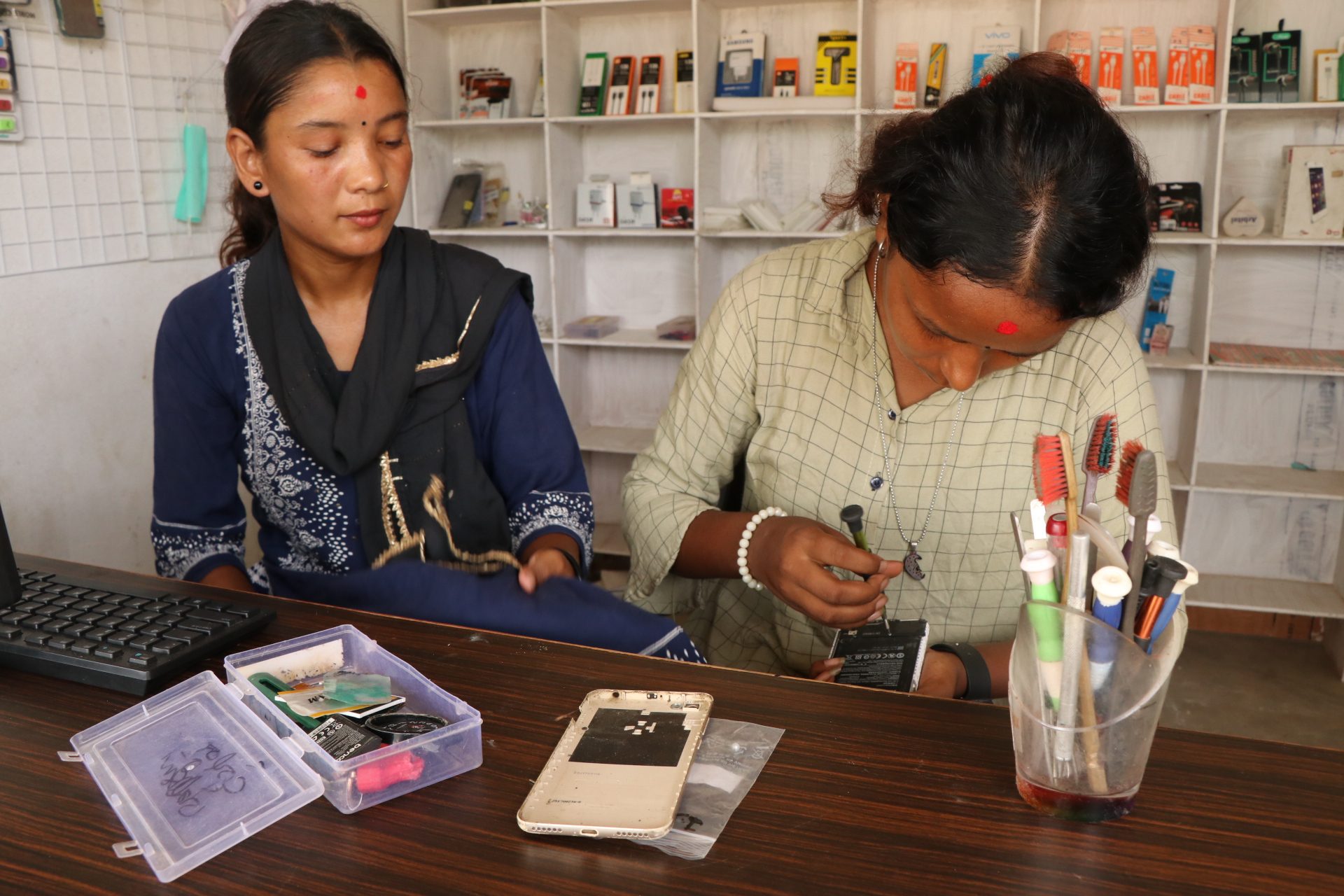 Ashmita and Anjali repairing a mobile phone.