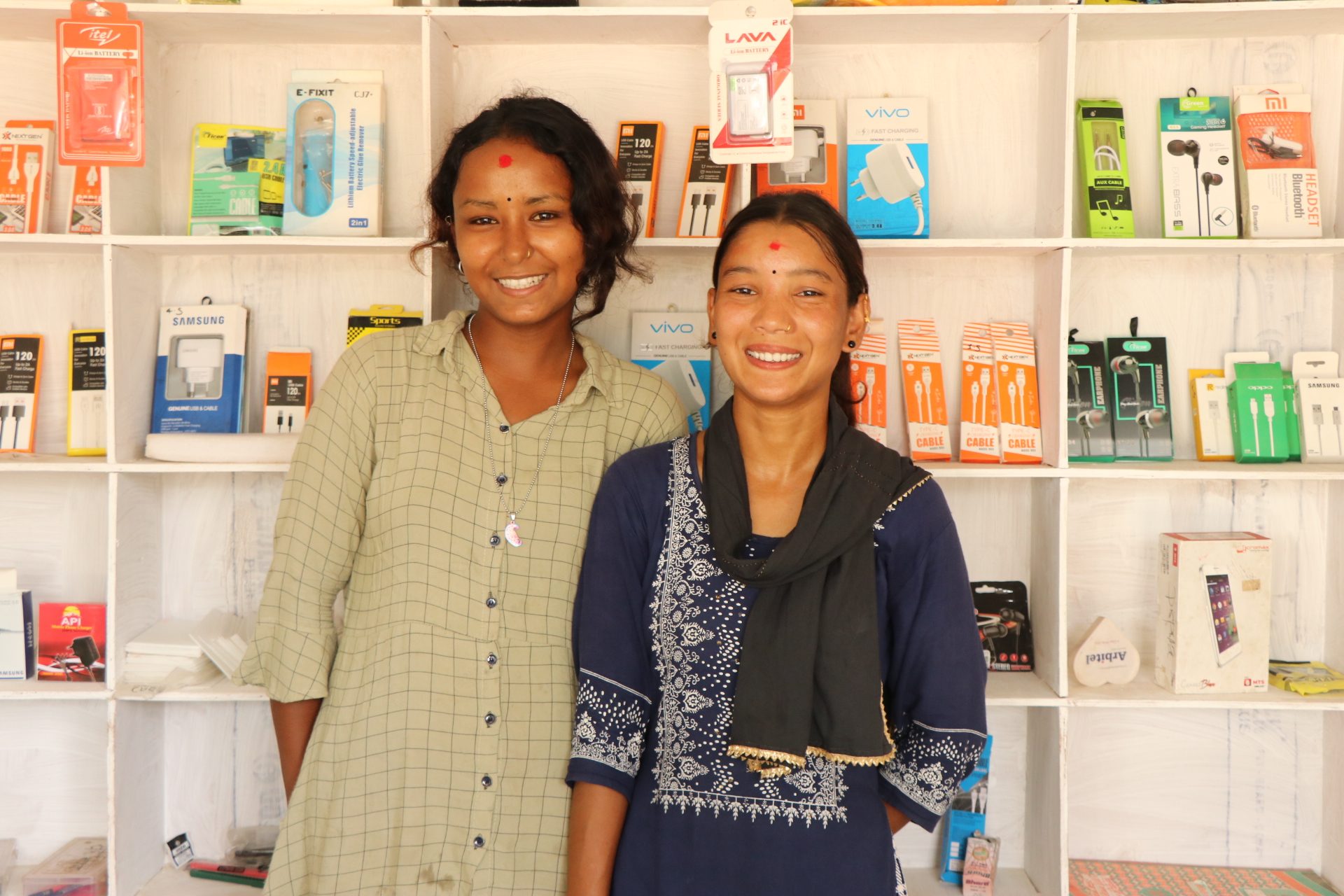 Ashmita and Anjila in front of the shelves in their mobile repair center. 