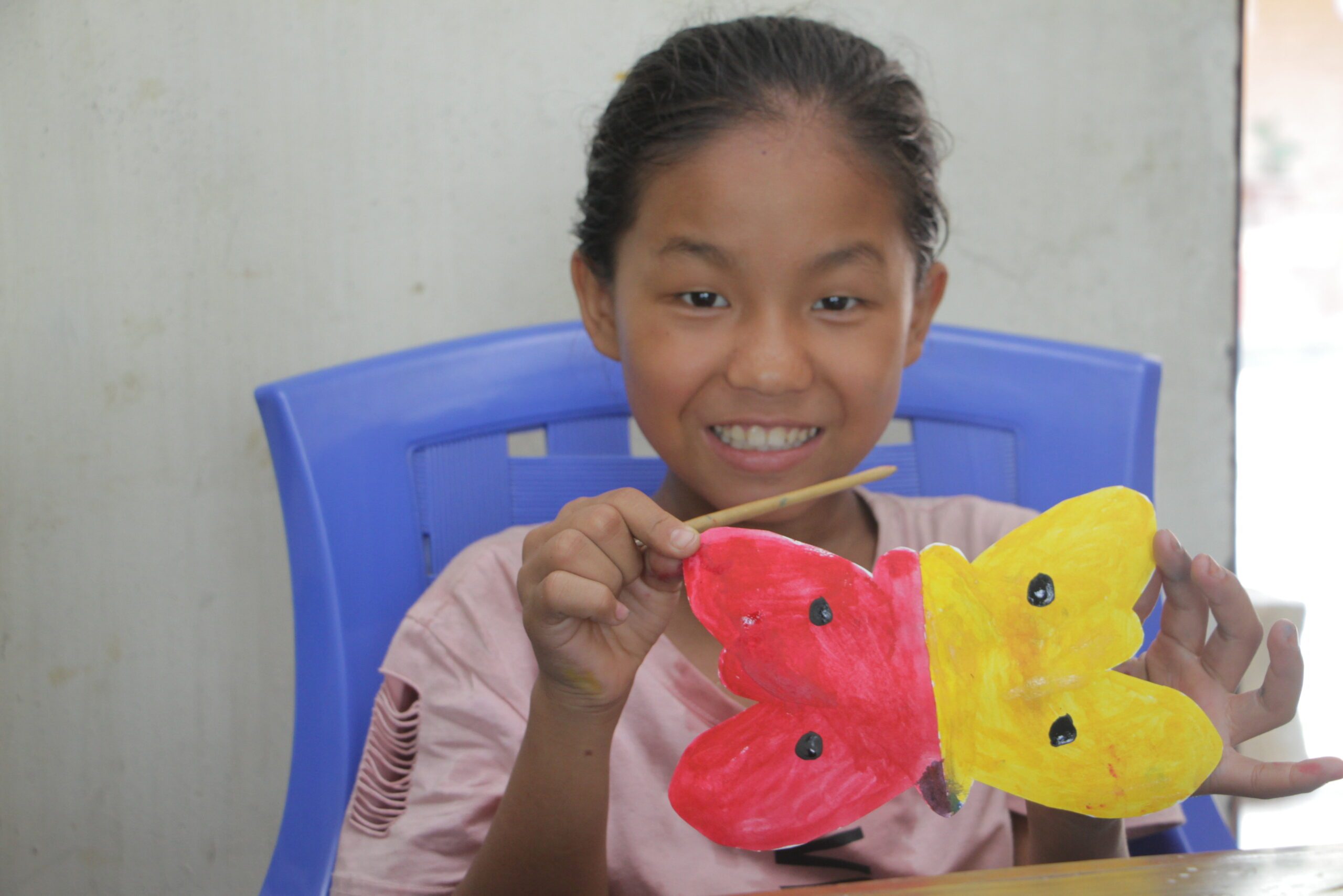 A girl showcasing her arts, a butterfly made during Art is Power workshop.