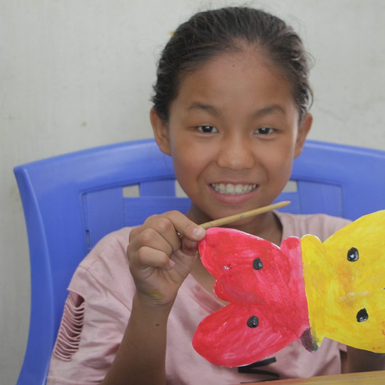 A girl showcasing her arts, a butterfly made during Art is Power workshop.