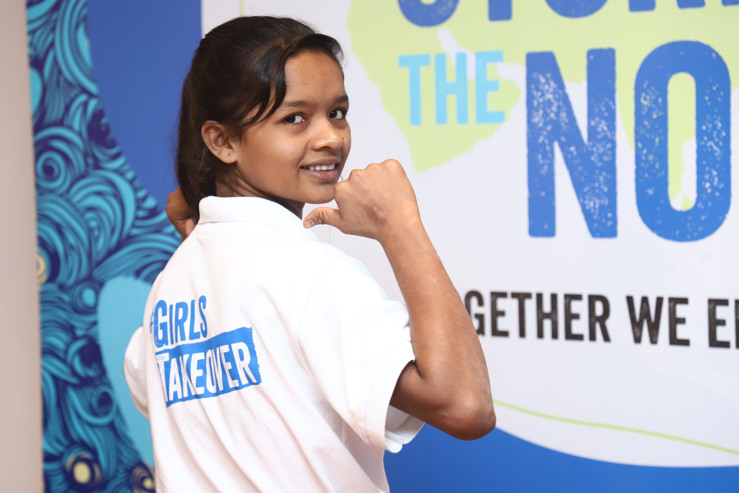 Neha looking into camera and pointing her finger at #GirlsTakeover design on her back.