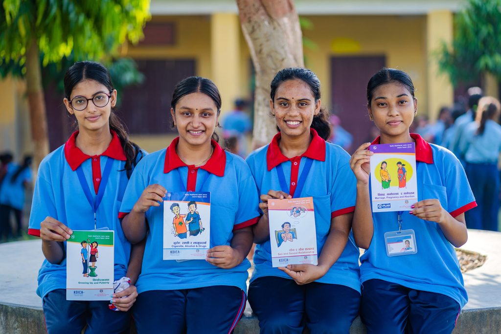 Four young girls are holding a book related to SRHR. 