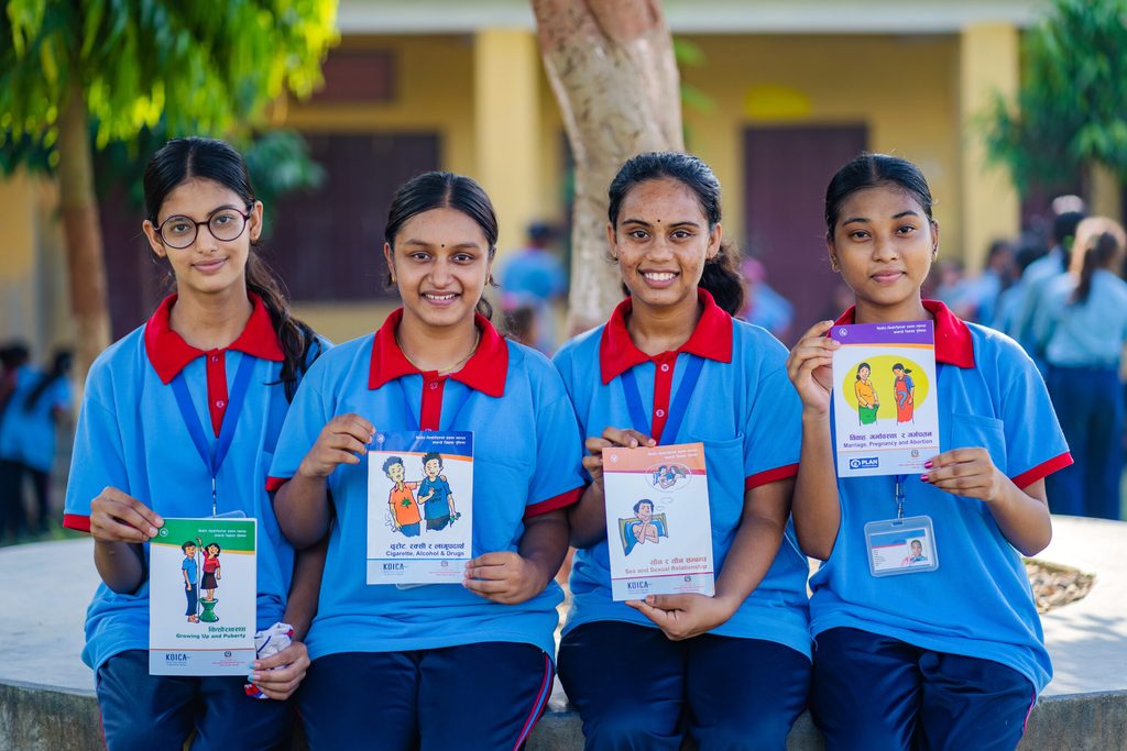 Four young girls are holding a book related to SRHR.
