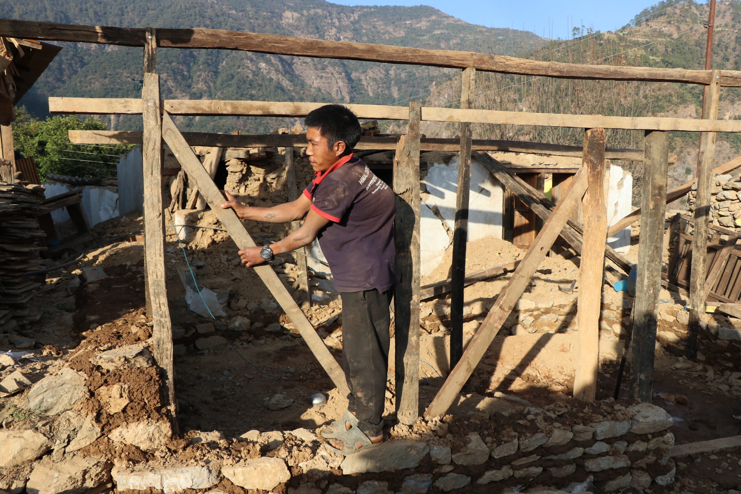 A man constructing a temporary shelter in his village. 