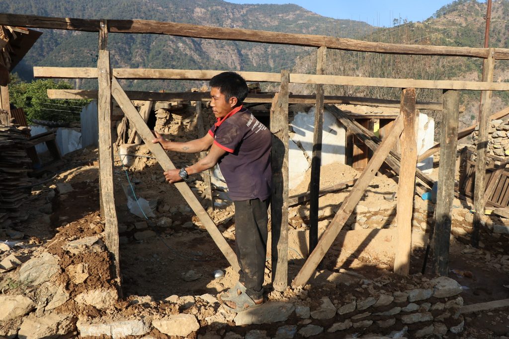 A man constructing a temporary shelter in his village.