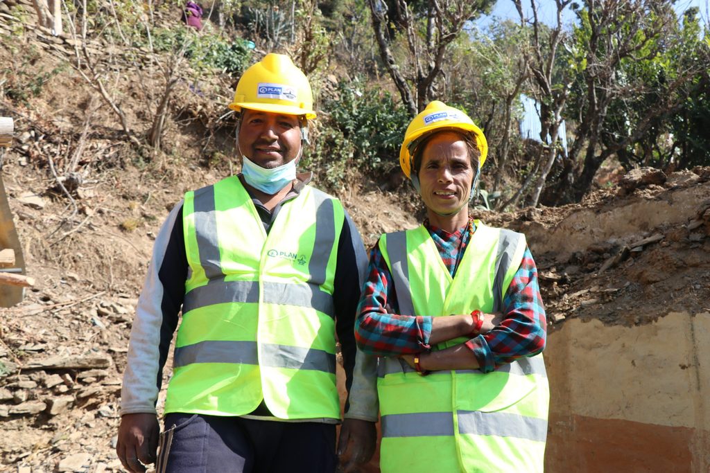 A man and woman wearing hardhat, standing with their arms fold.