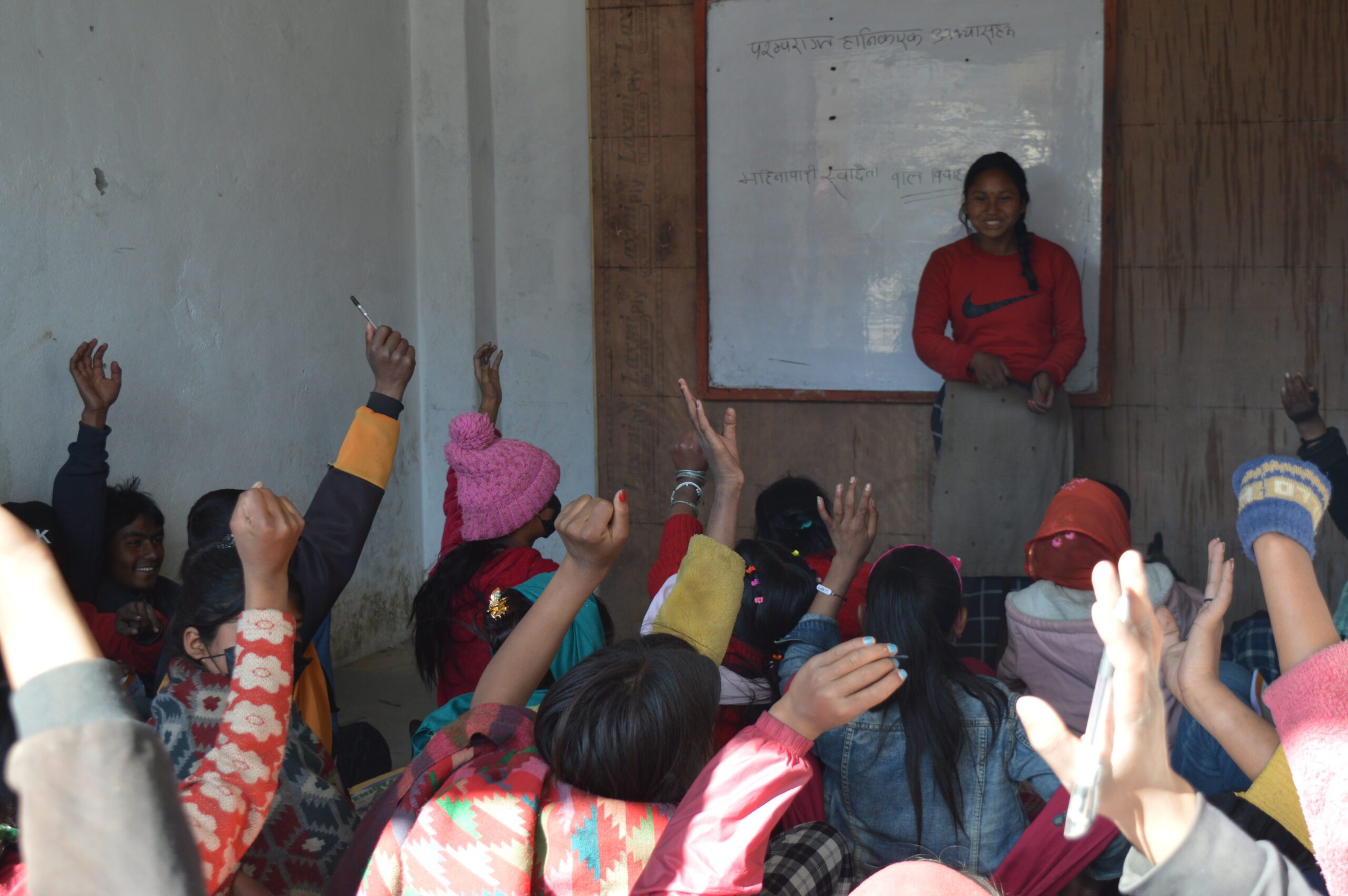 Attima talking at the front of a group session, with a group of girls raising their hands.