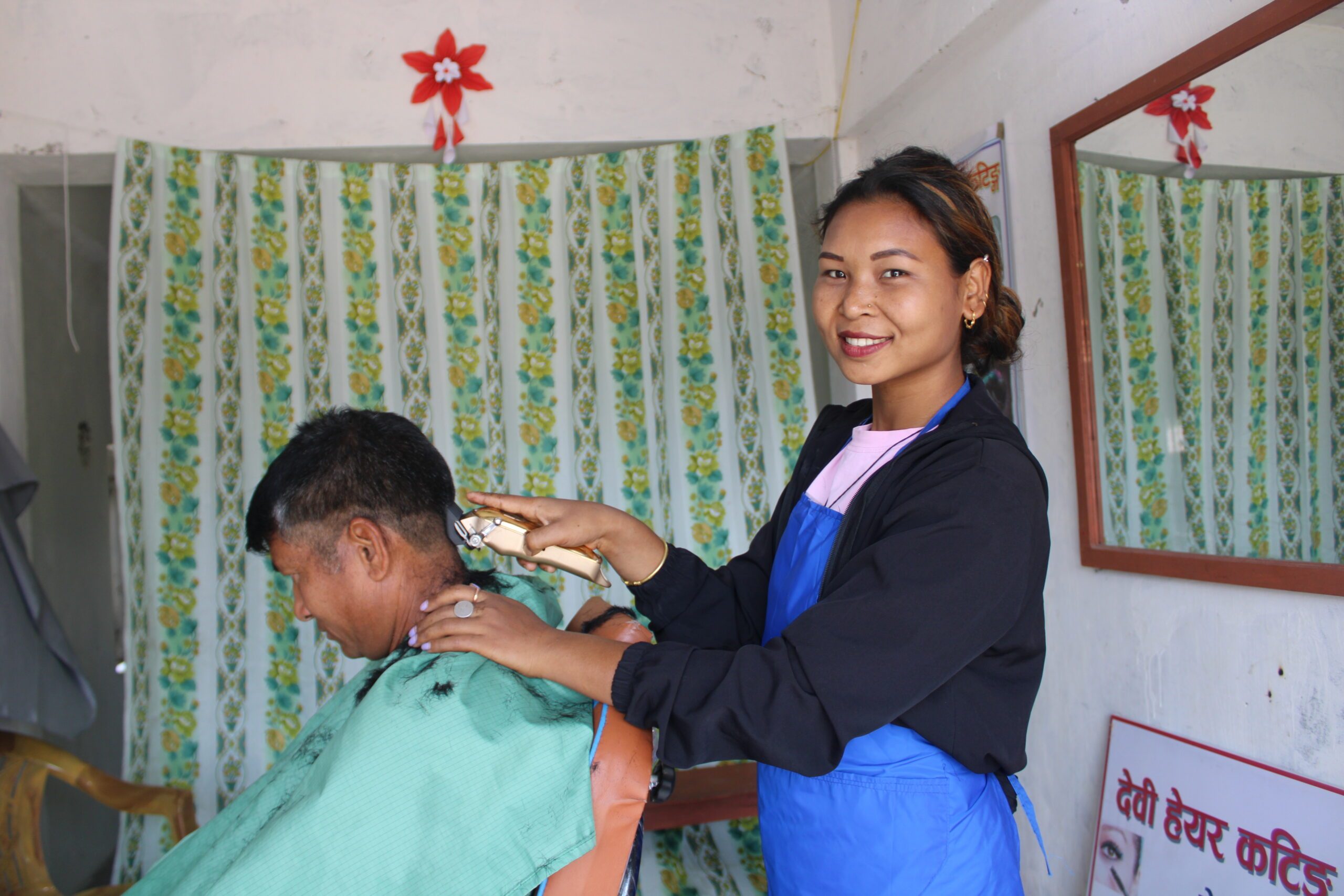 Devi in her salon cutting hair of a customer.