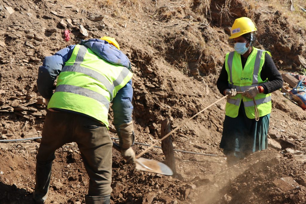 Parbir and Deepa wearing yellow vest, hard hat and working to clear debris in their house.