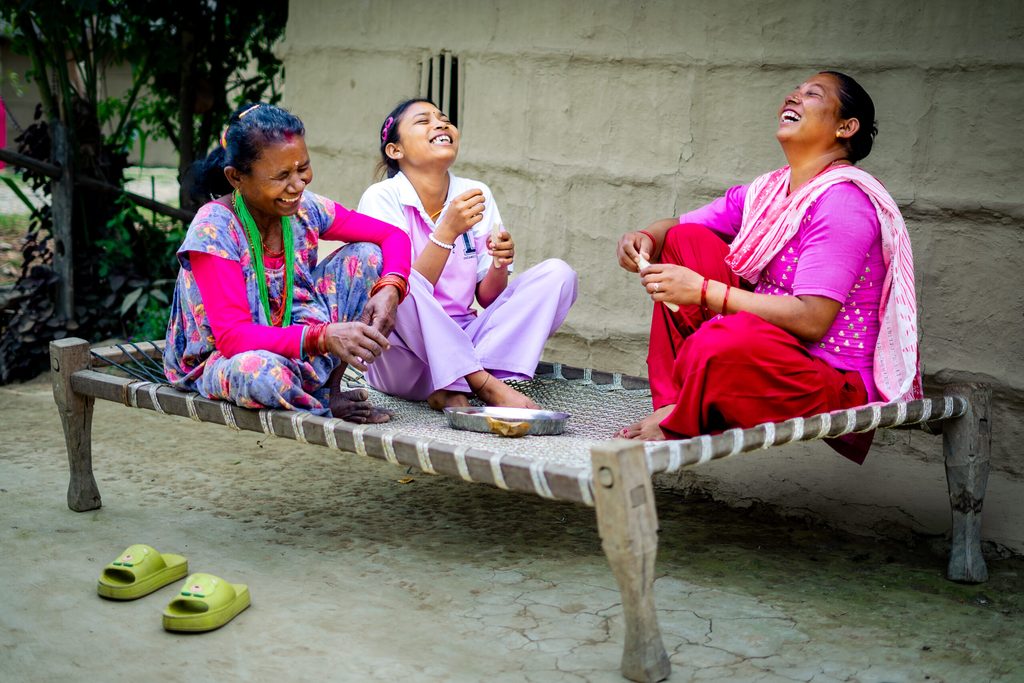 Three women enjoying snack together and laughing.