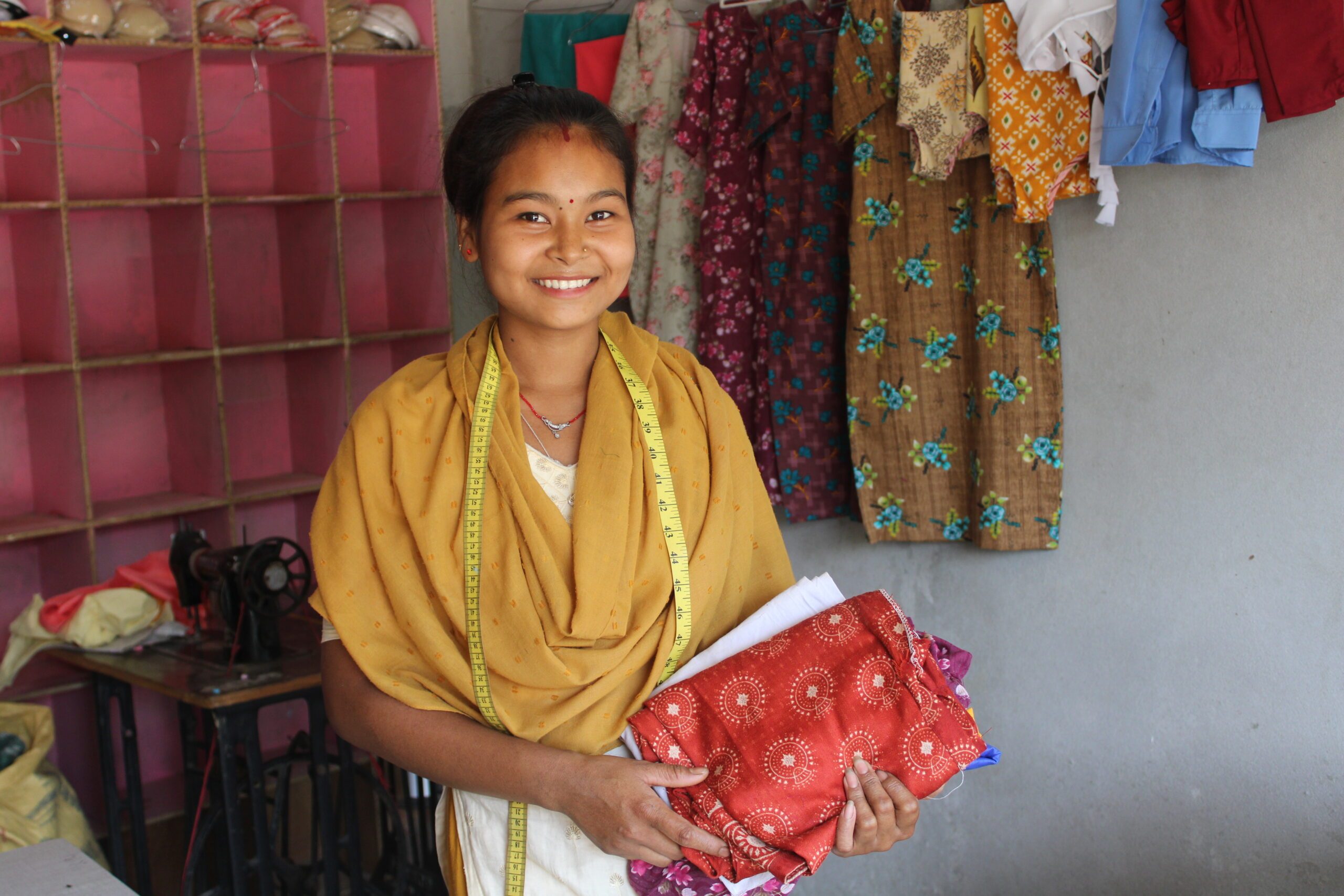 In her tailoring shop, Aarati delicately holds a handful of garments, inspecting them with care.