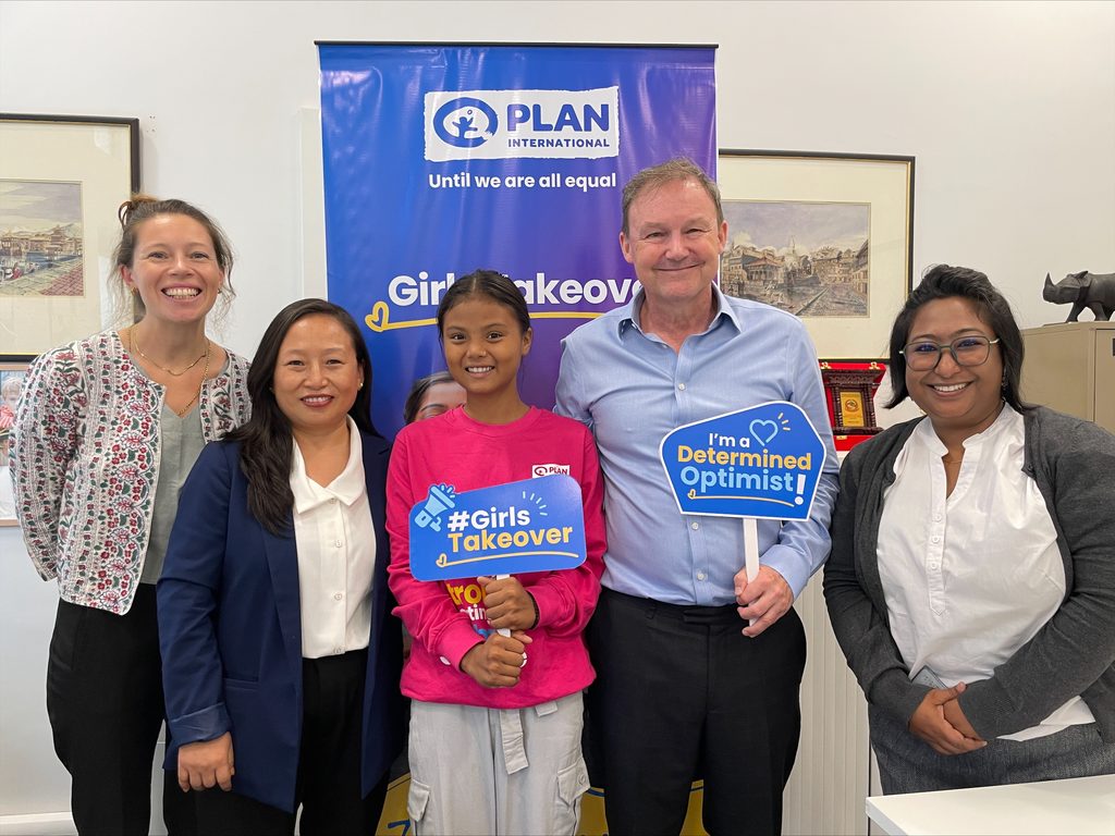Sima is wearing pink sweatshirt in the middle posing with embassy and Plan team.