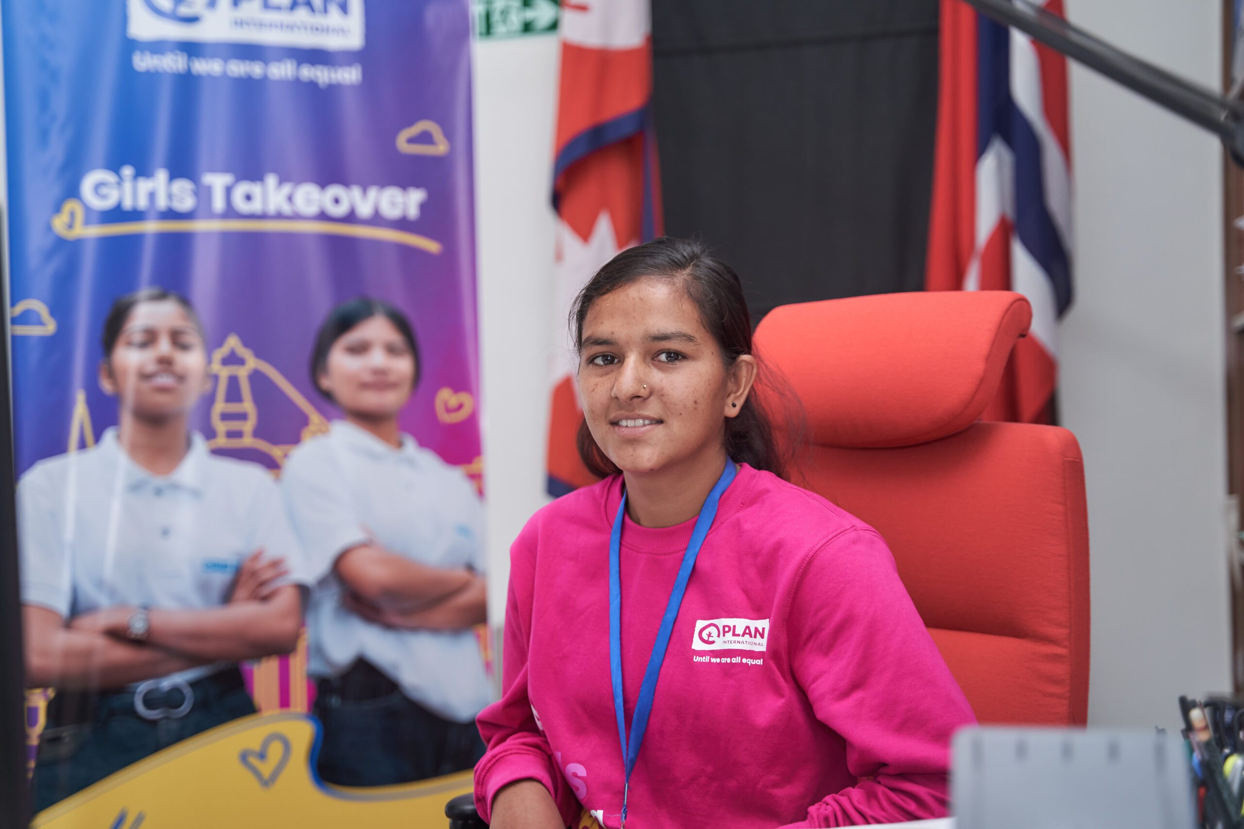 Lalita wearing pink sweatshirt sitting on the chair of Norwegian Ambassador. 