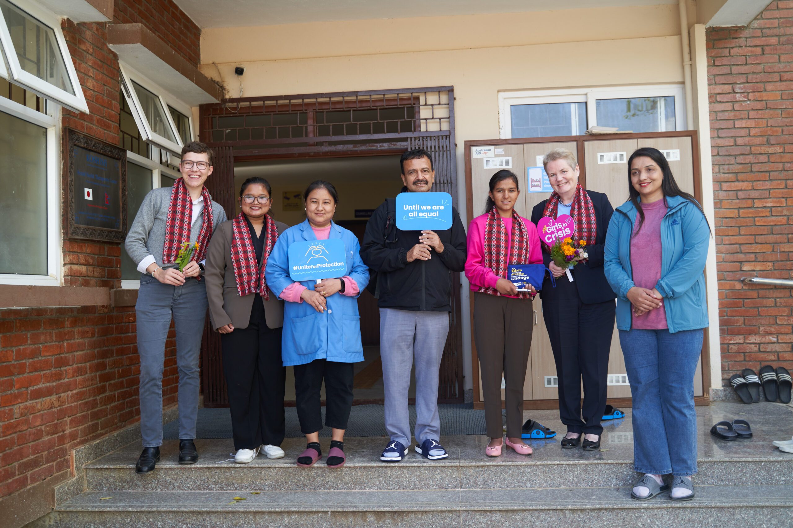 Lalita with H.E. Torun and Koshish team holding placards. 