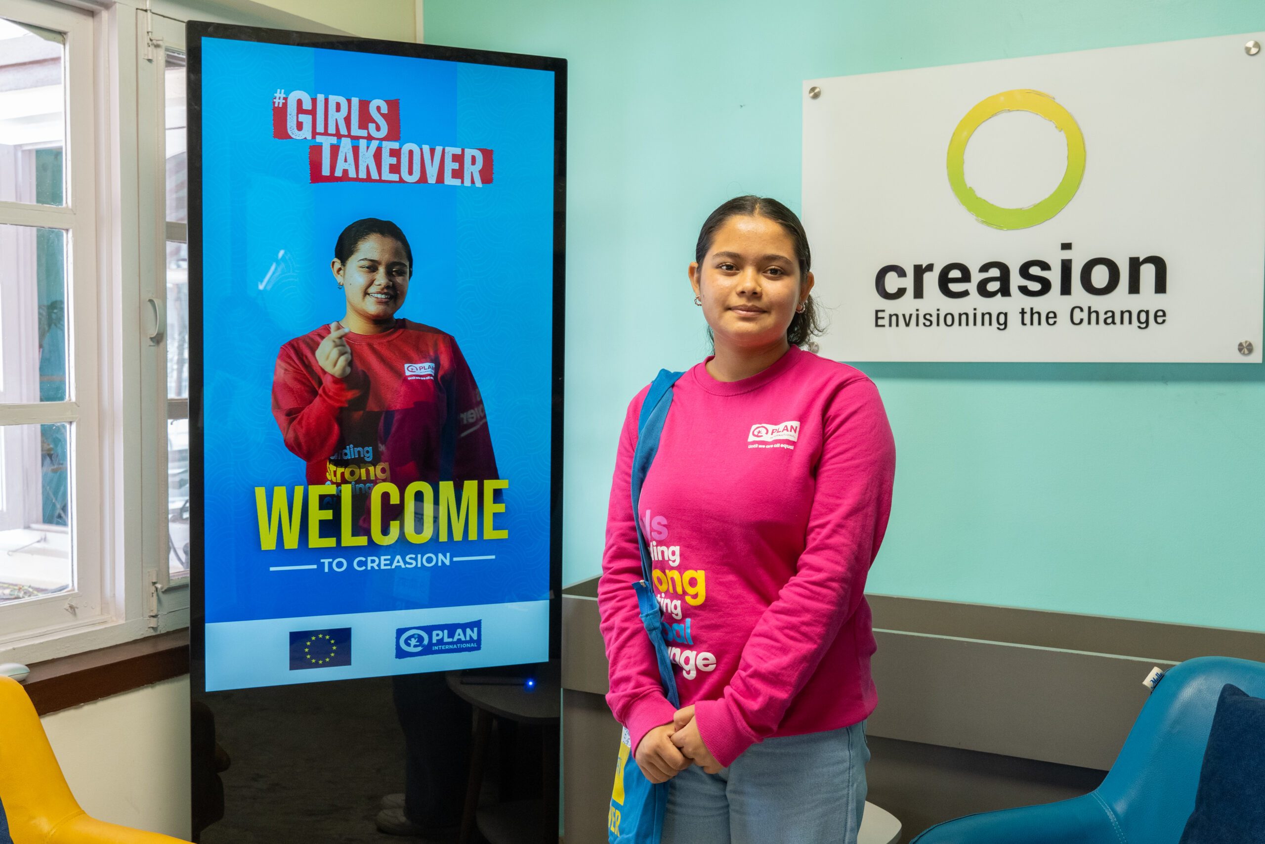 Ranjita standing in front of display with her photo where Girls Takeover is written.