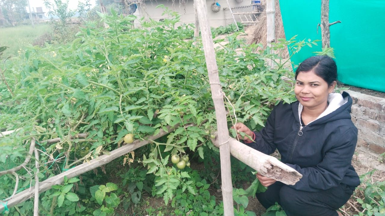 A young female wearing black jacket sitting and working in her garden.