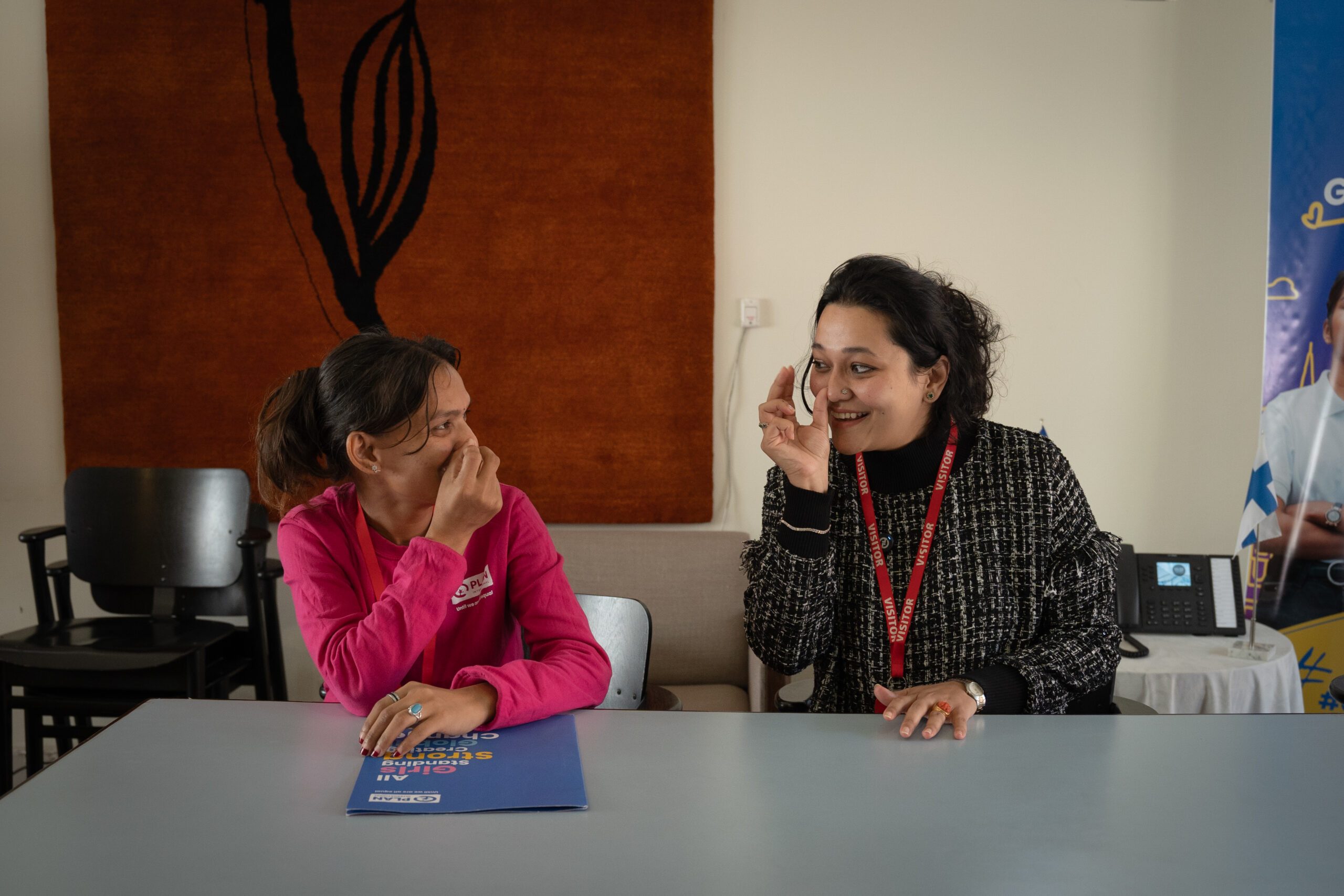 Balkumari on left using sign language with Aayushi, the CEO of Khalisis on right. 