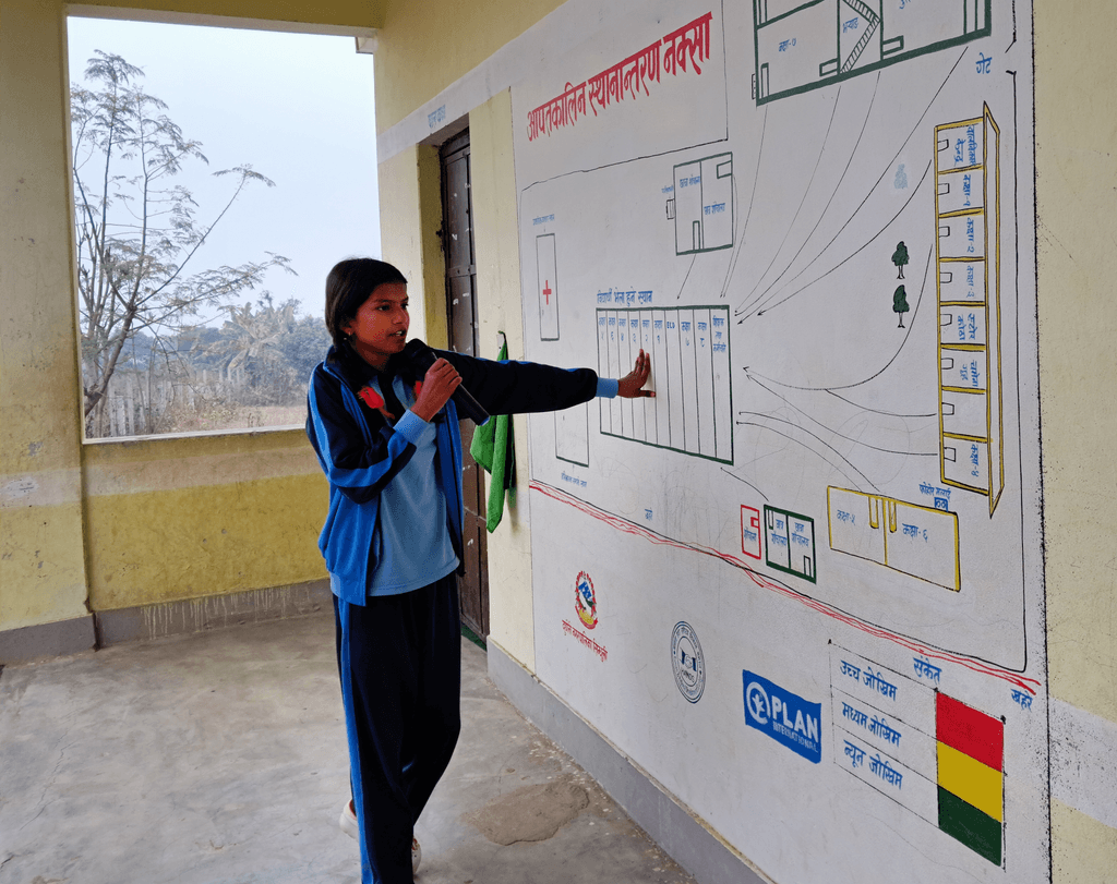 A female student pointing on her school wall and reading using the mic.
