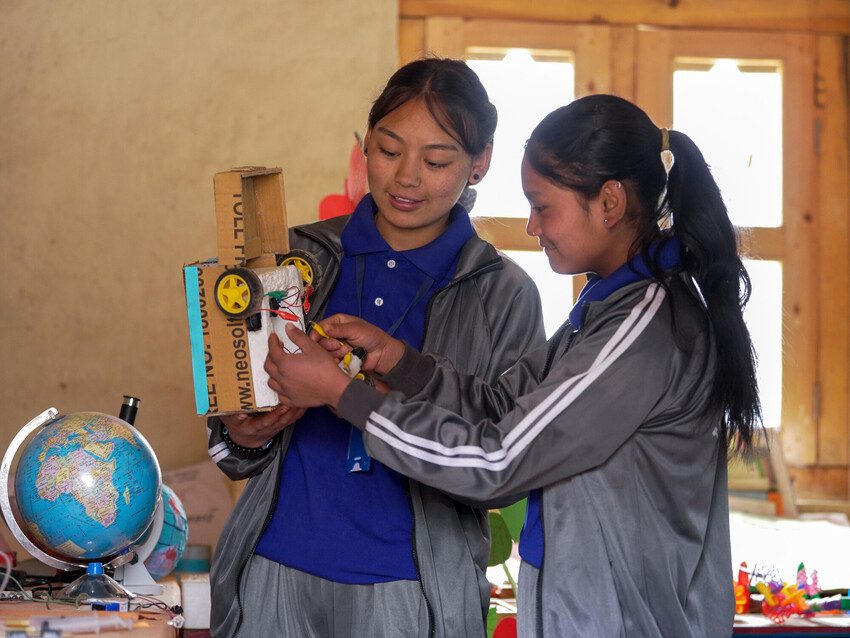 Two girls are working on building a robotic model. 