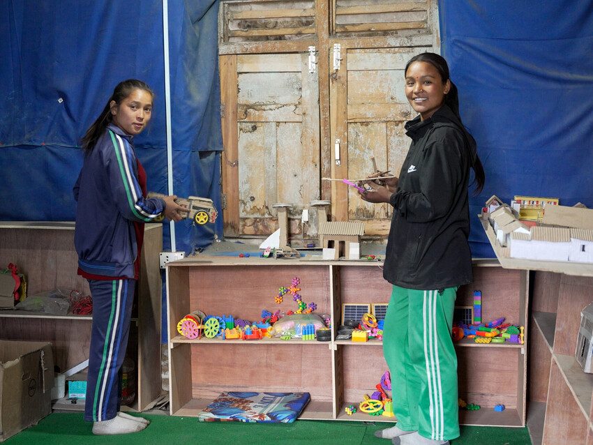 Two girls hold up models made by classmates. 