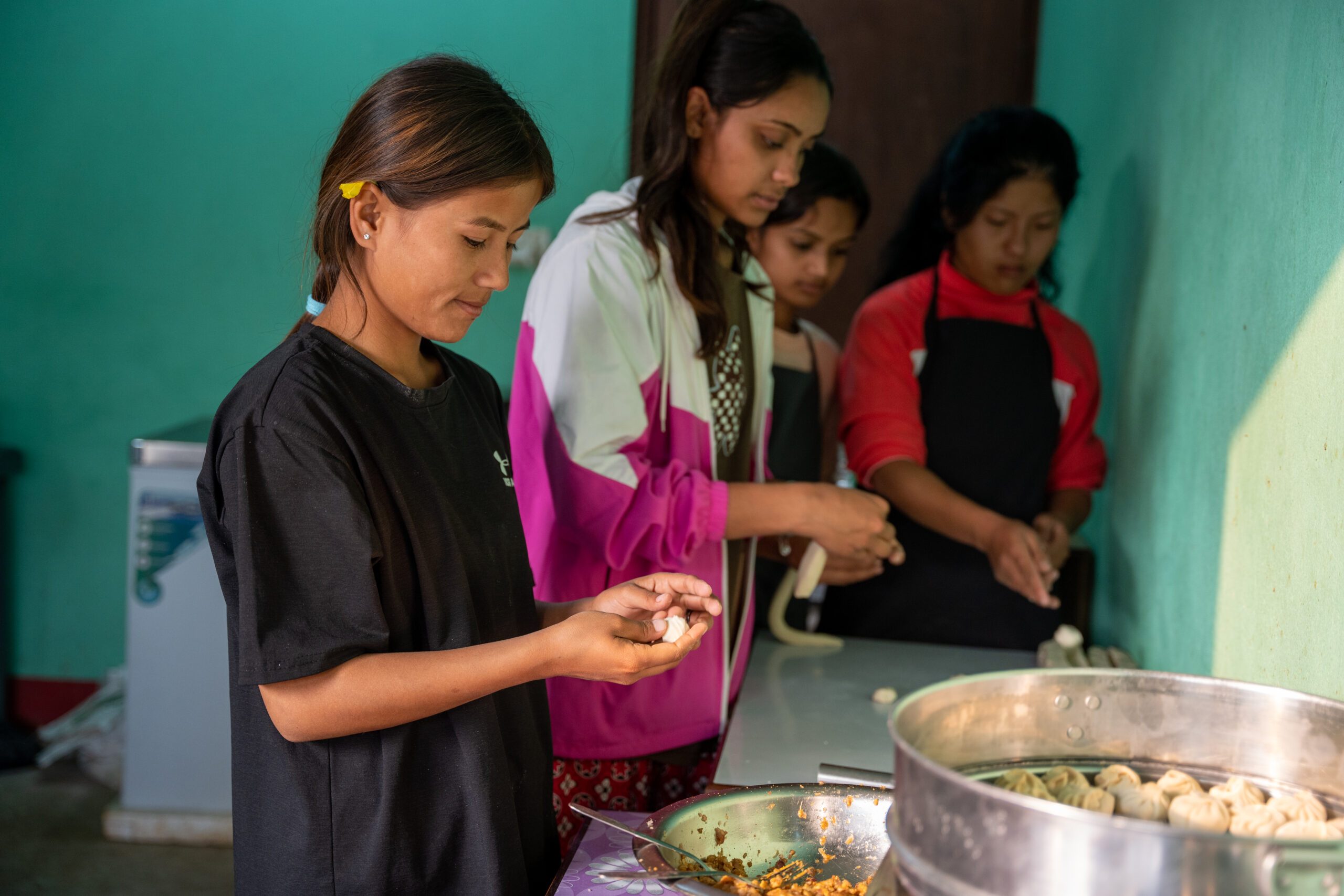Four girls in kitchen making momo.