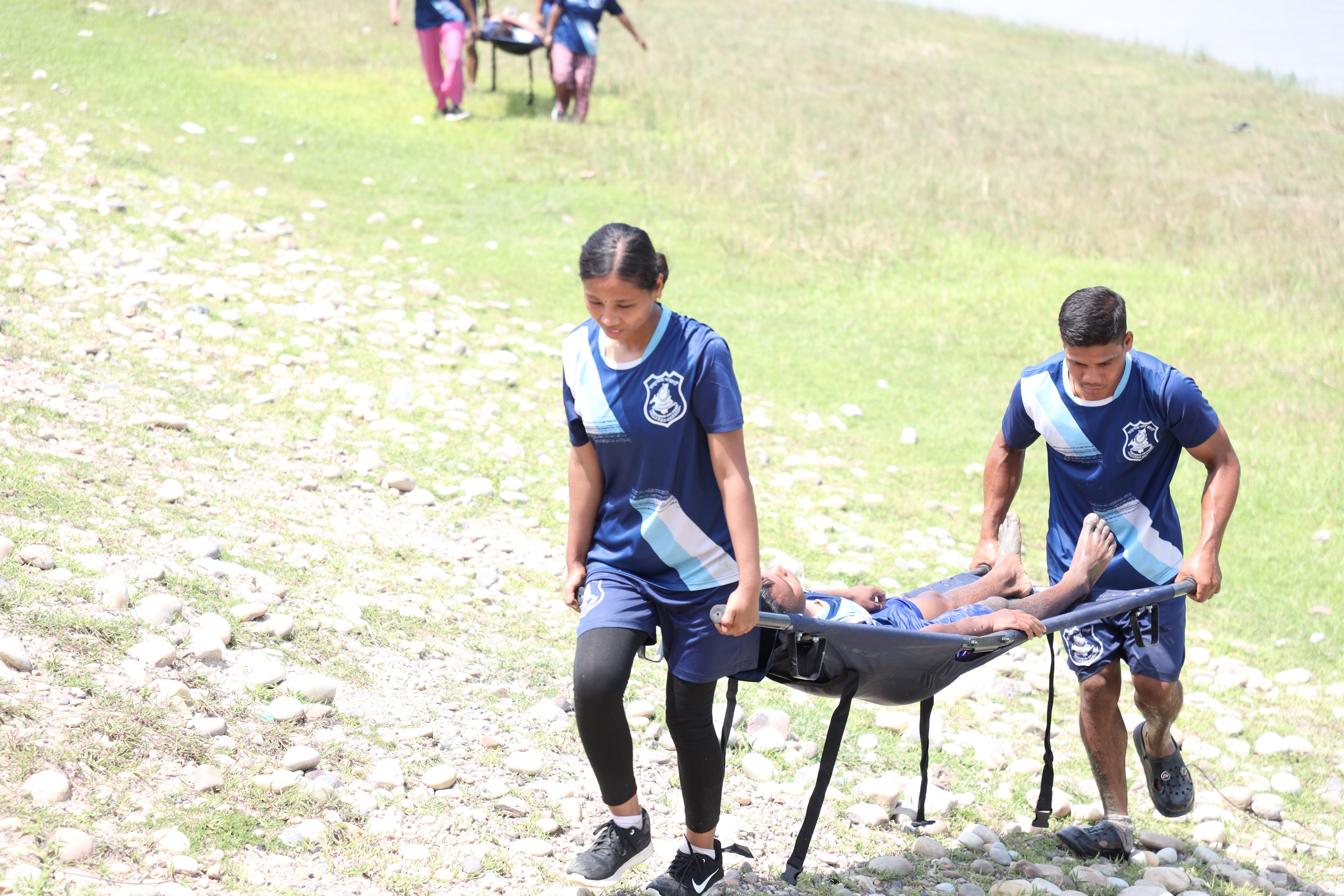 A woman (in the front) and a man (at the back) carrying a person in stretcher during stimulation drill