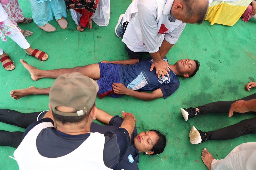 Participants practise CPR on a training dummy during a flood preparedness drill in Thakurbaba, learning lifesaving techniques for emergencies.