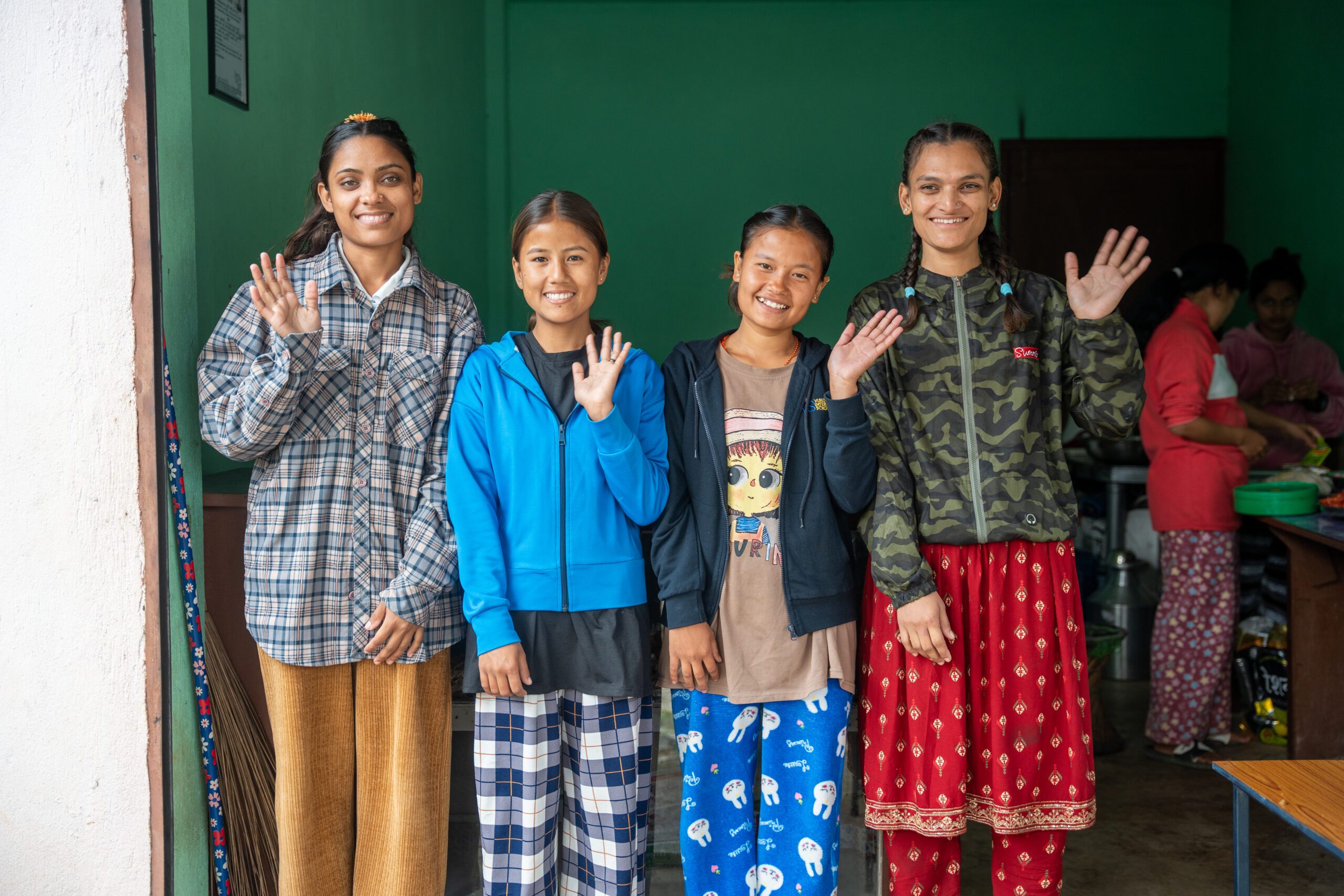 Four deaf young girls standing and waving. 