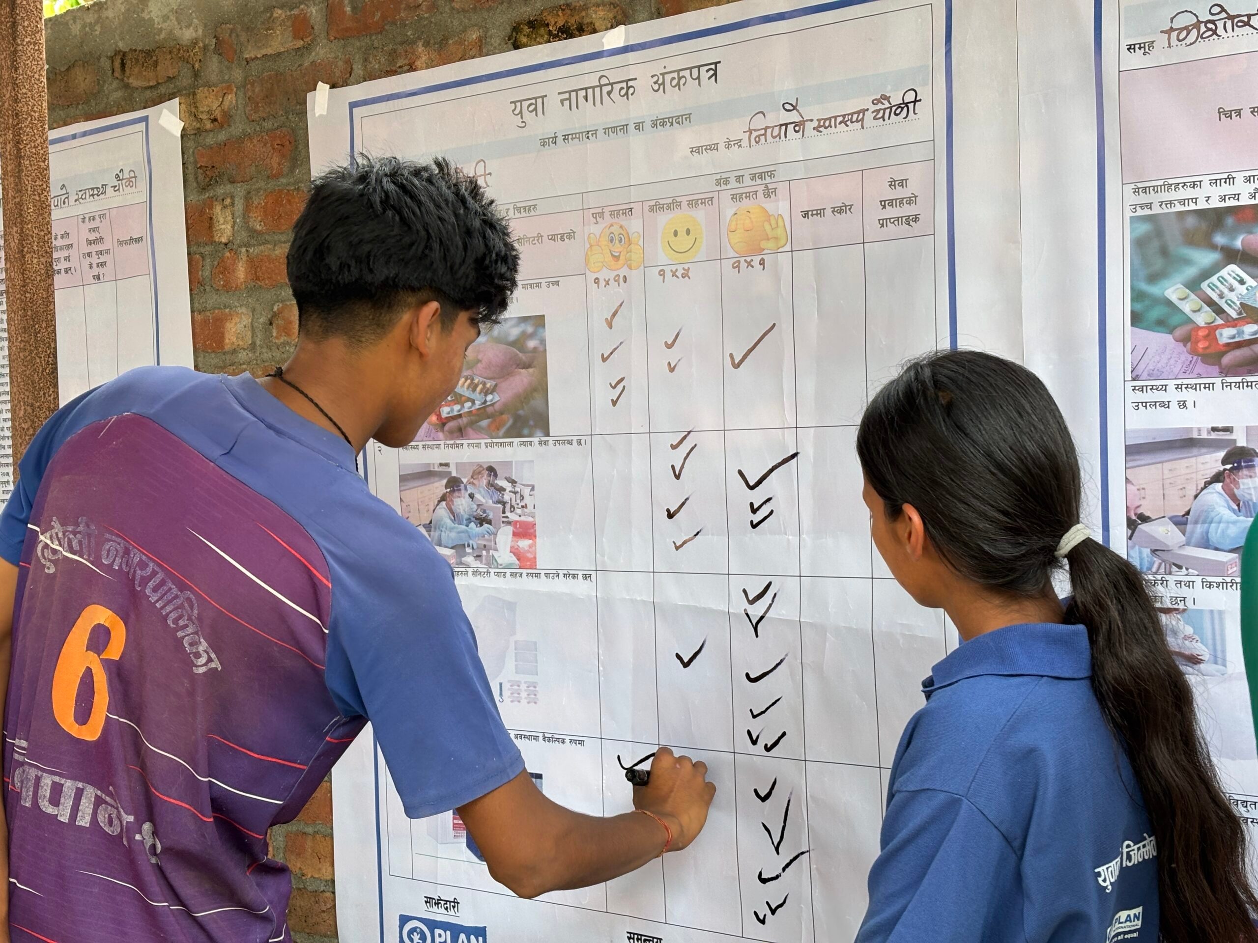A boy (left) and Youth volunteer (right) ticking the YCSC in the community.