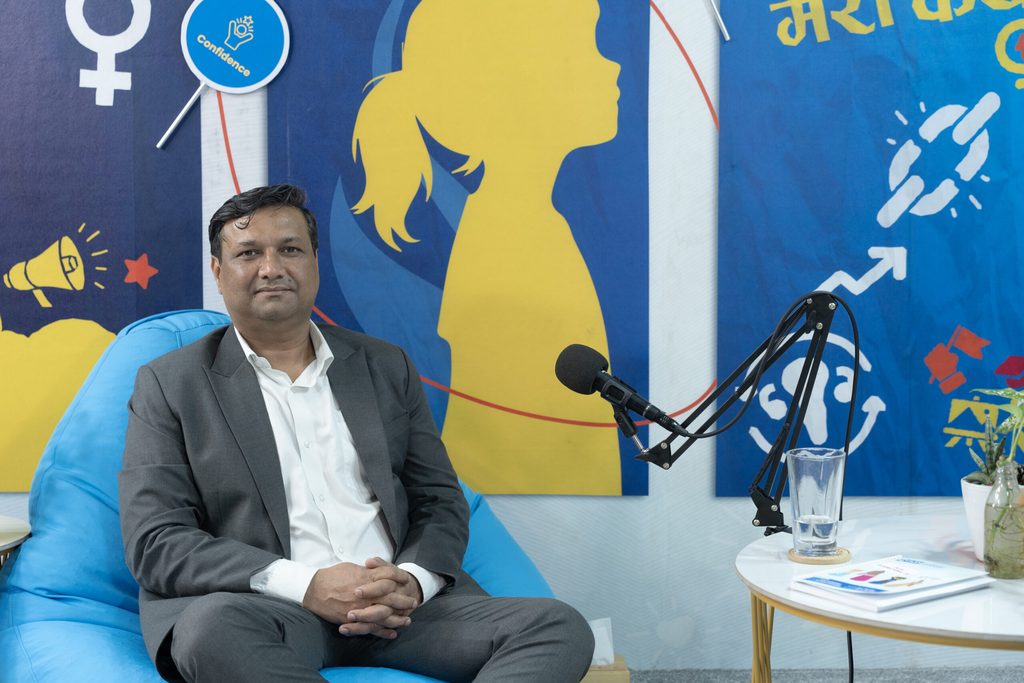 Country Director, Ram sitting in a bean bag, in front of him is mic and being part of Podcast.