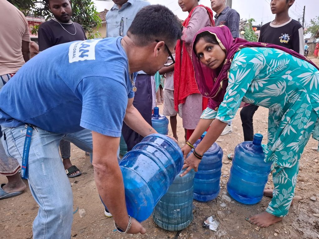 Plan staff on left supporting a woman on right during the clean drinking water response.
